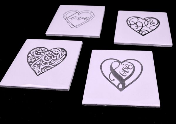 Image of engraved white coasters with decorative heart design - Donley Woodworking